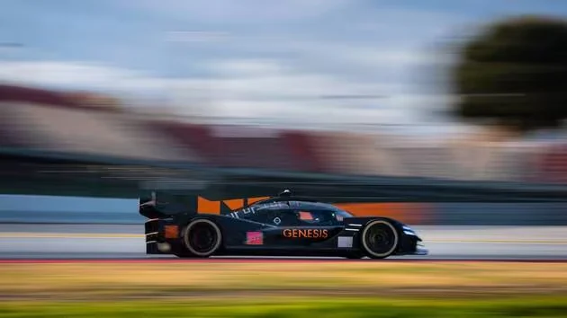 The Genesis Magma Racing GMR-001 hypercar at speed, the grandstands blurred behind it